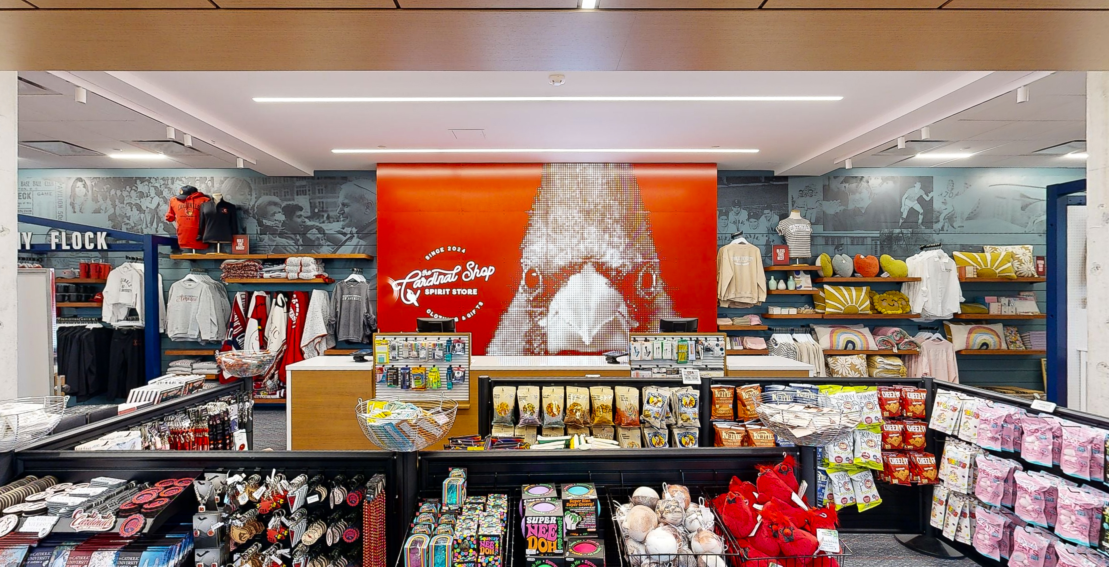 The finished Cardinal Shop — a Cardinal-pride pixel mural anchors the checkout, framed by black-and-white archive walls