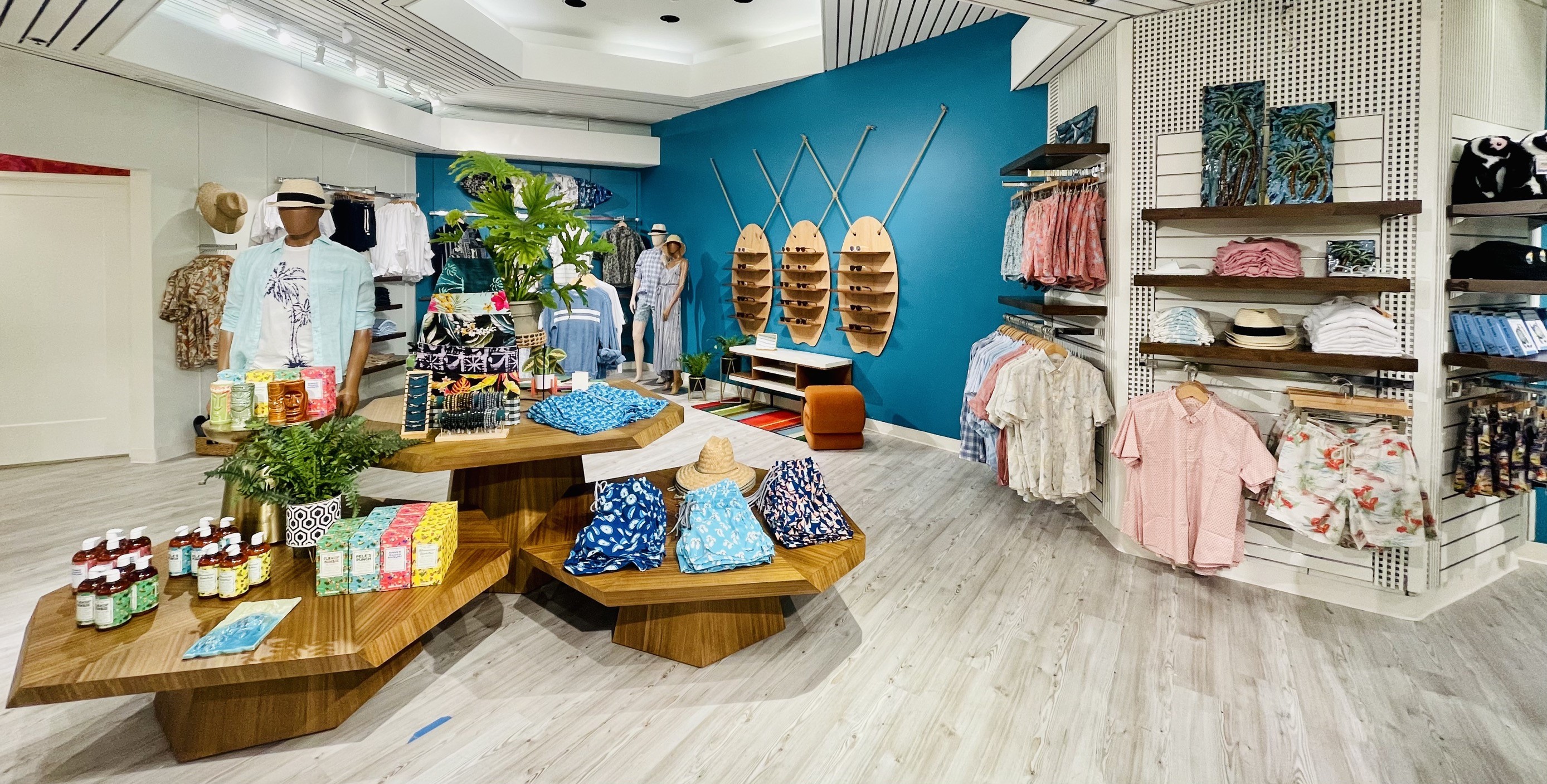 The men’s shop — aloha prints, surfboard sunglass displays, and a teal feature wall