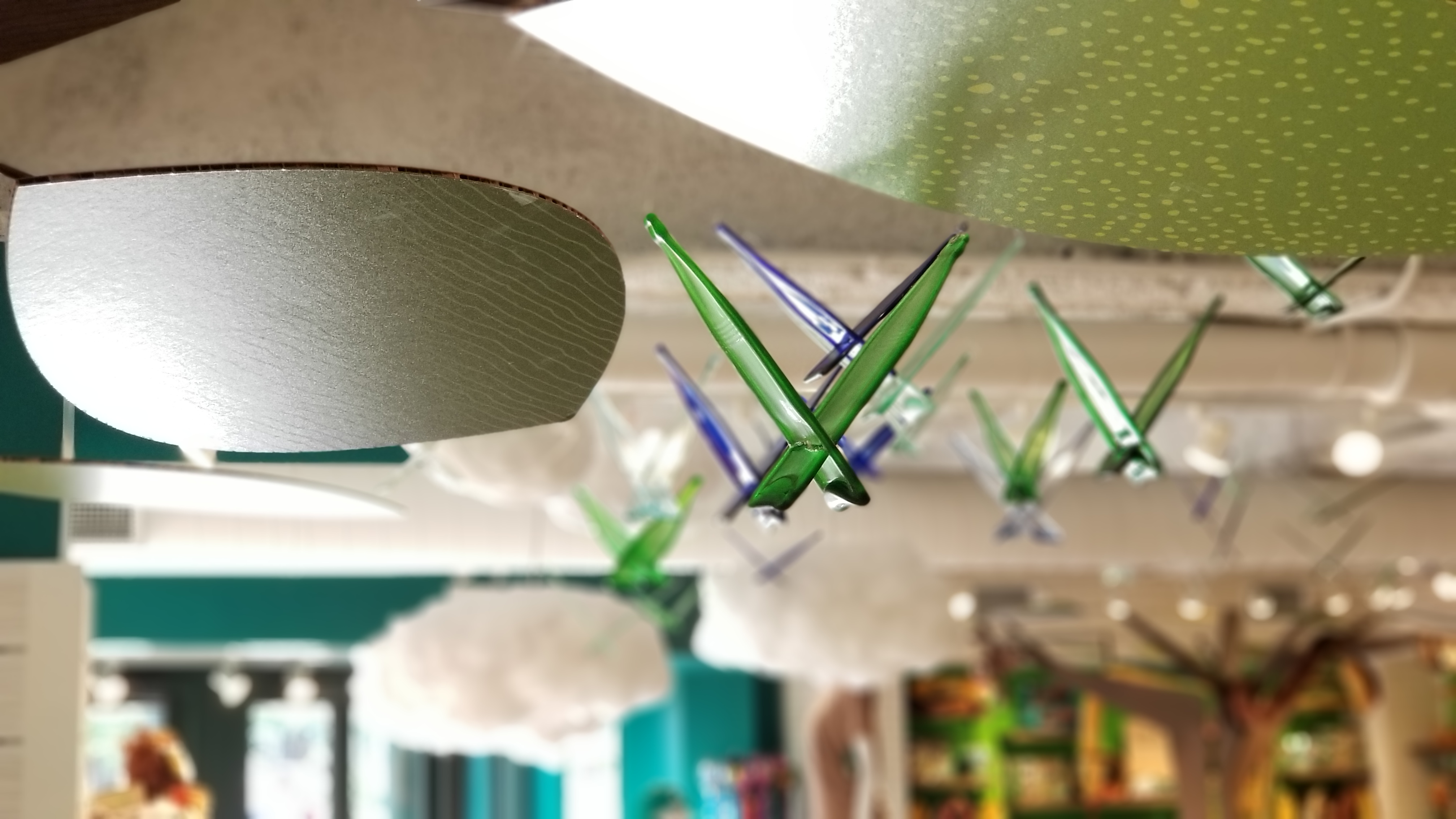 Glass origami birds in flight overhead — a handmade flock celebrating the natural world