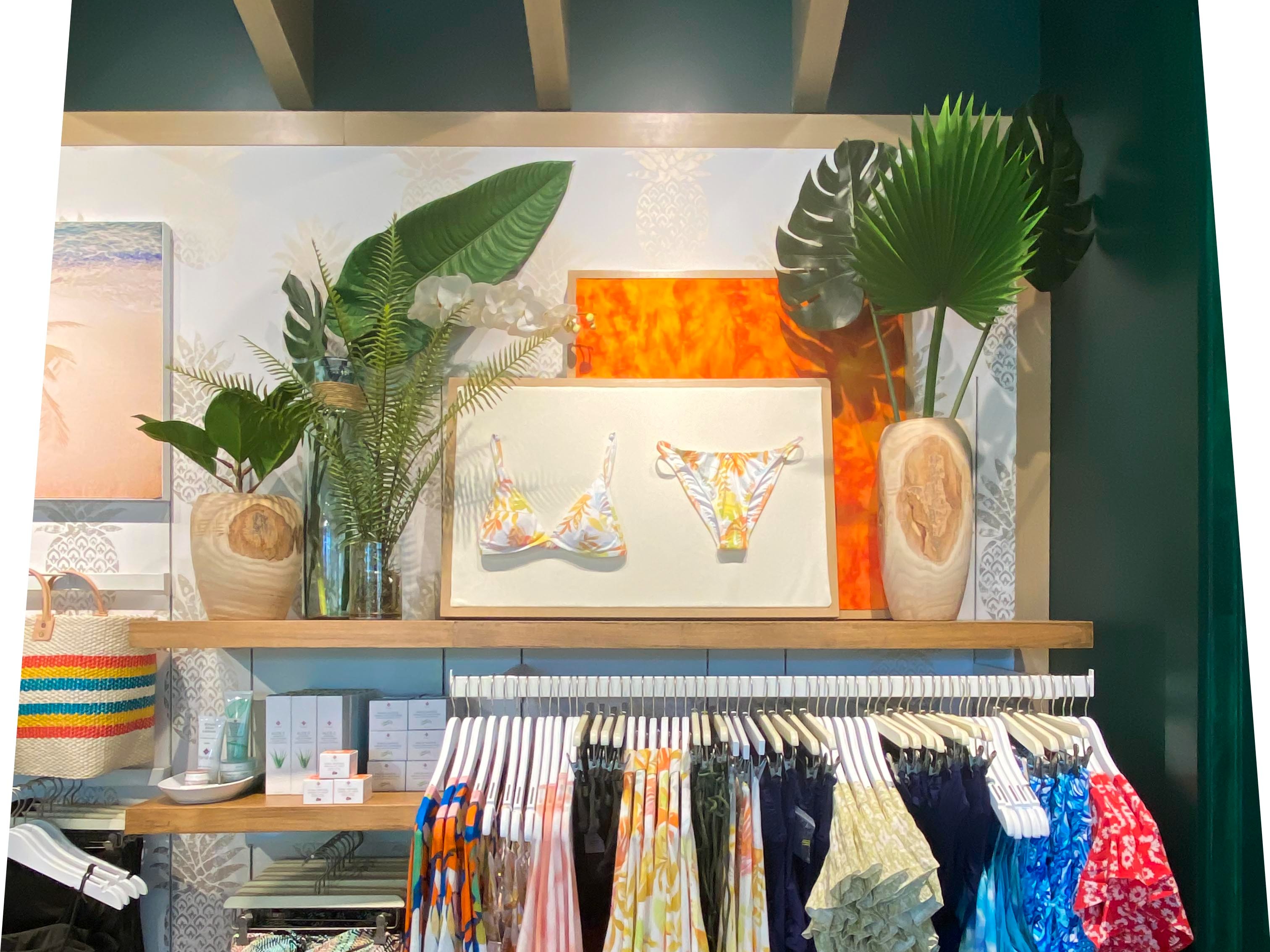 The swim-and-coverup wall, framed by woven naturals and tropical foliage