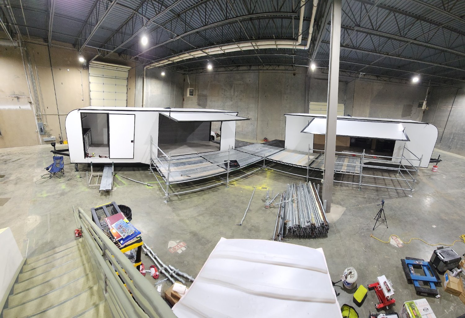 Two trailers mid-build in Truman's shop — sidewalls open, decks and railings going in before they hit the road